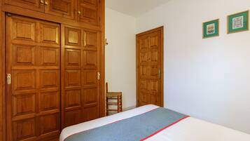 Un dormitorio con cama, armario de madera y dos cuadros en la pared.