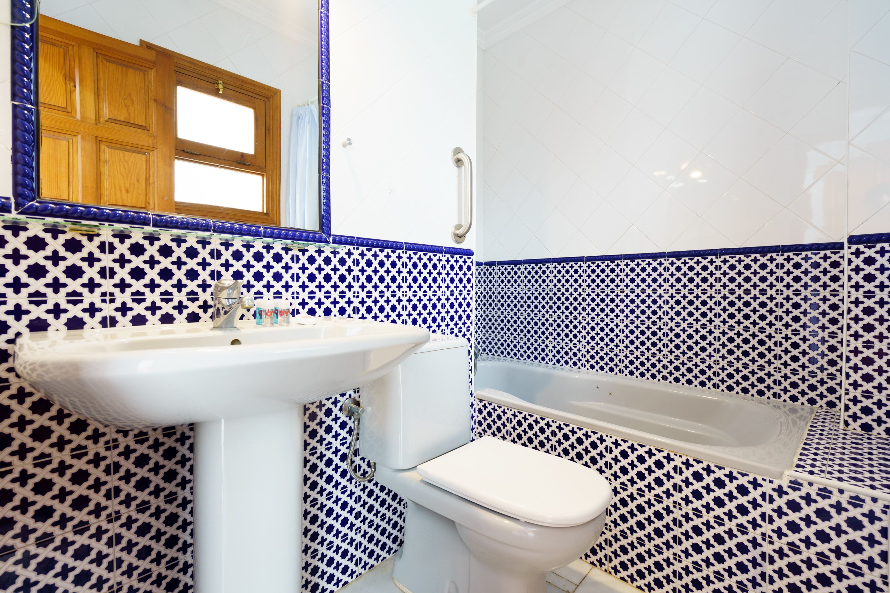 A bathroom with a sink, toilet, and bathtub, all with blue and white patterned tiles.