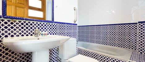 A bathroom with a sink, toilet, and bathtub, all with blue and white patterned tiles.