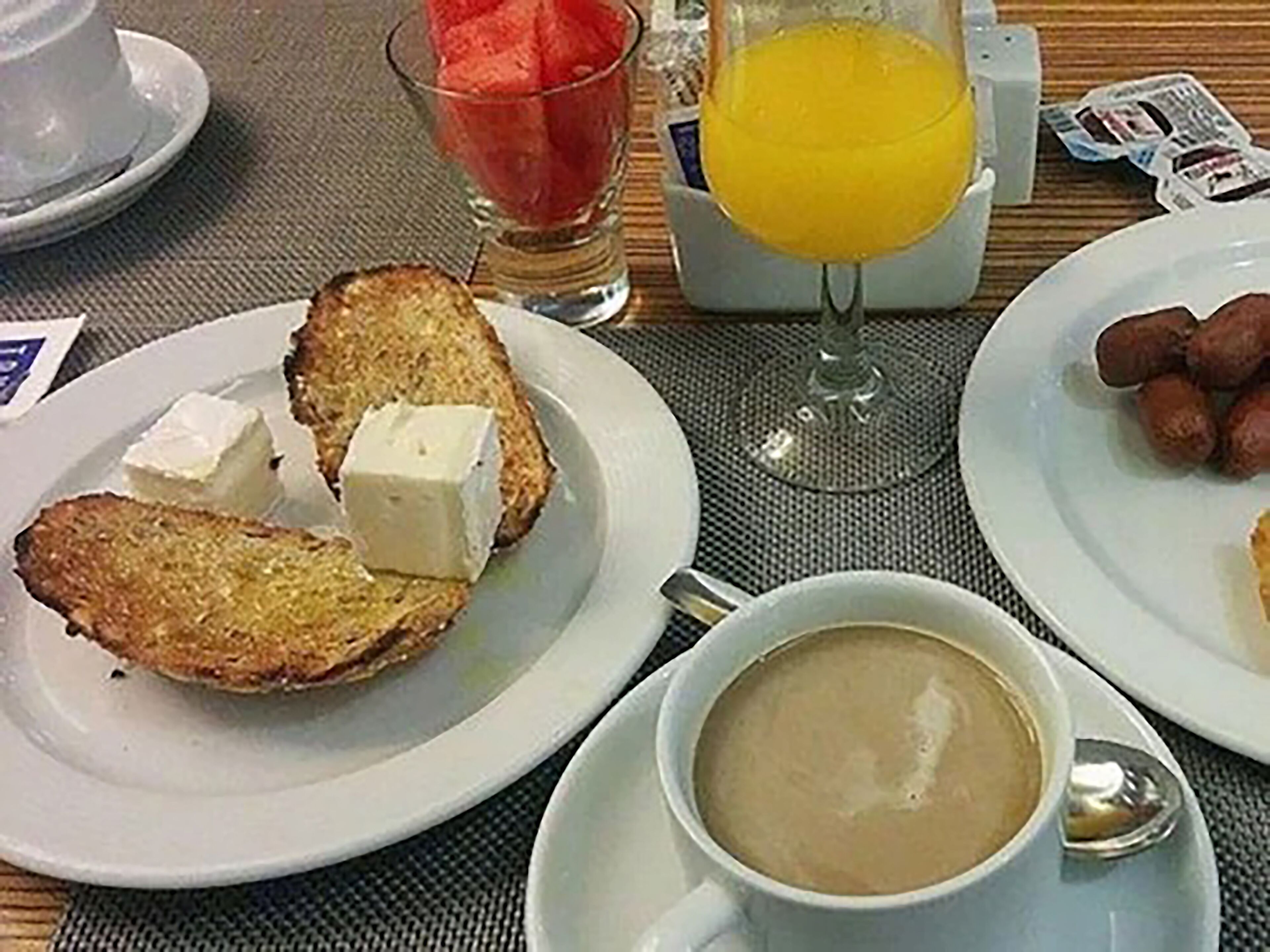 A breakfast setting with toast, butter, jam, coffee, and a glass of orange juice on a table.