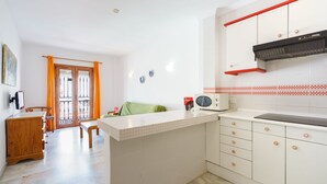 Una cocina con armarios blancos, microondas y una campana extractora roja.