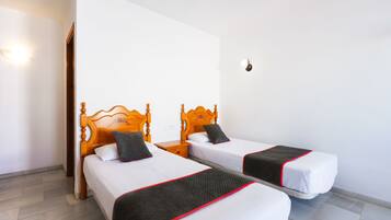 A hotel room with two wooden beds, white bedding, and a red trim.