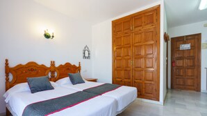 Un dormitorio con una cama doble, un armario de madera y una mesita de noche.