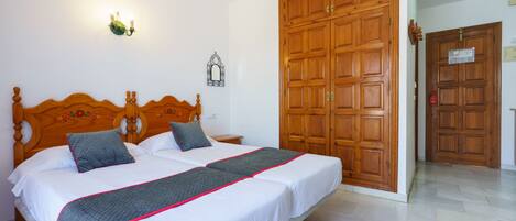 A bedroom with a double bed, a wooden wardrobe, and a nightstand.