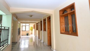 A hallway with a polished floor, wooden doors, and a window with a wooden frame. - Weygoss Guest House (Addis Ababa)