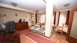 A hotel lobby with a reception desk, a sofa, a TV, and a wooden cabinet. - Weygoss Guest House (Addis Ababa)