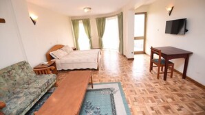 A room with a bed, a sofa, a table, and a TV. - Weygoss Guest House (Addis Ababa)