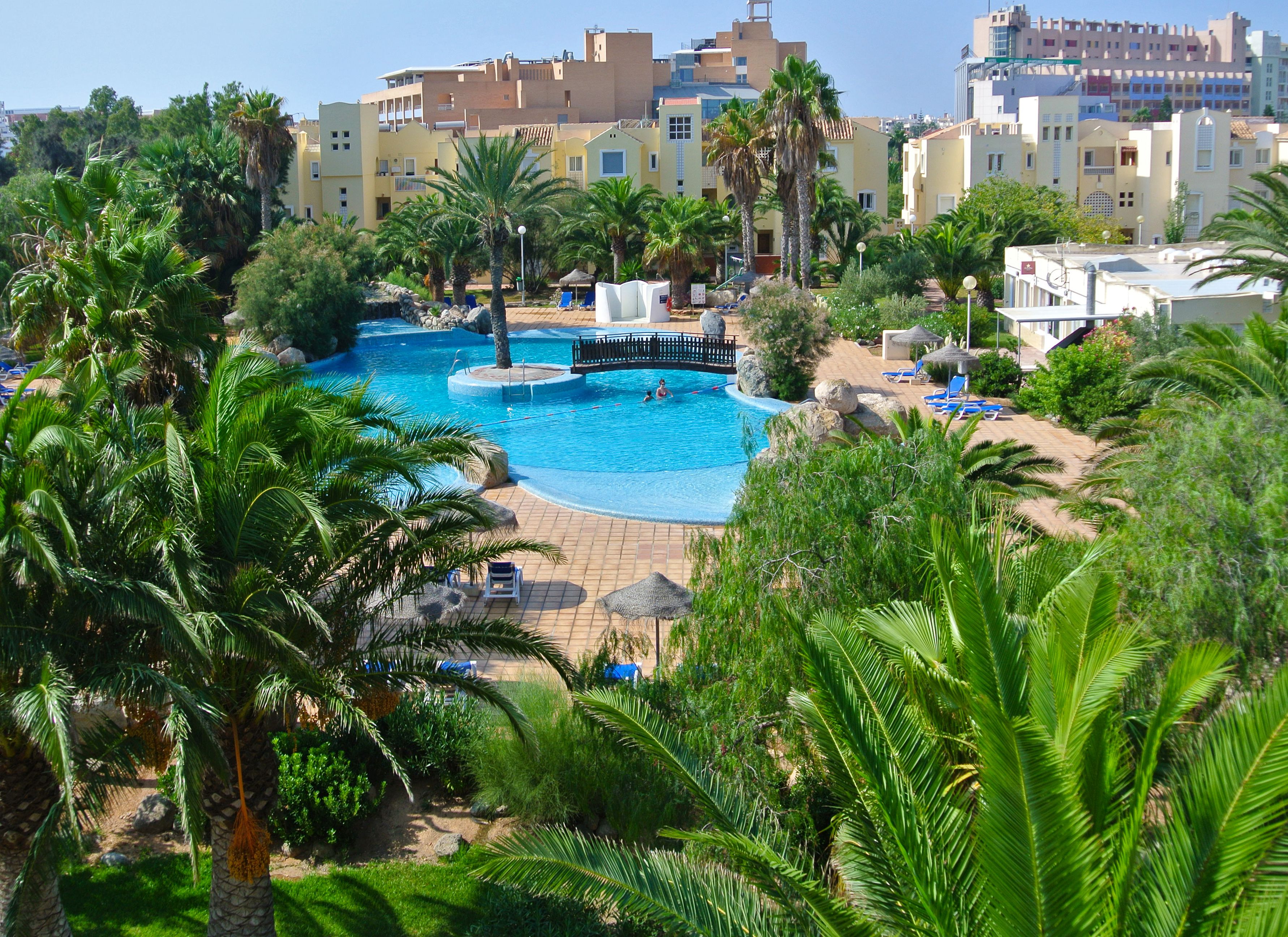 Un resort con una gran piscina rodeada de palmeras y tumbonas.