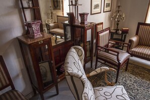 Une pièce meublée de meubles anciens, notamment des chaises et des tables, et ornée d’un miroir.