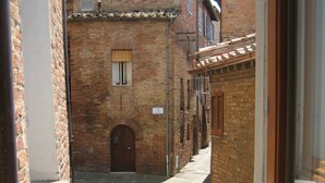 Un callejón estrecho con edificios de ladrillo, una puerta de madera y un ventanal pequeño.