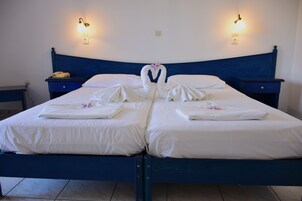 Una cama doble con sábanas blancas y un arreglo de toallas con forma de cisne.