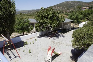 Una terraza en la azotea con un columpio, una zona de estar cubierta y vistas a un paisaje montañoso.