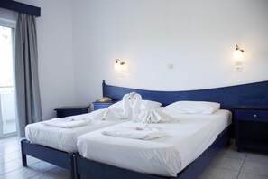 A hotel room with a bed, two bedside tables, a wall-mounted lamp, and a window with curtains.