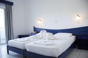 A hotel room with a bed, two bedside tables, a wall-mounted lamp, and a window with curtains.
