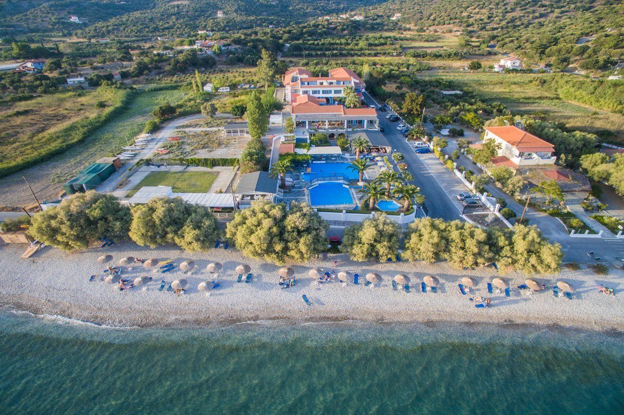 Eine Vogelperspektive eines Küstenhotels mit Schwimmbad, Strand und umliegender Bepflanzung.