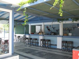 Un área de bar al aire libre con mostrador, taburetes y una persona atendiendo.