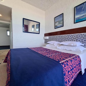 Una habitación de hotel con una cama, un espejo y dos cuadros en la pared.