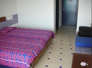 Una habitació amb un llit, una taula petita i una porta.