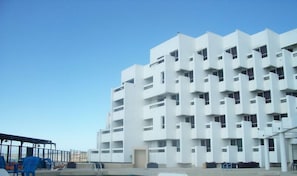 Un edificio moderno de varios pisos con fachada blanca y balcones.
