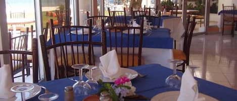 A restaurant with tables set for dining, featuring blue tablecloths and white napkins.