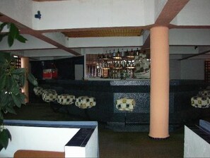 A bar area with a counter and stools, surrounded by pillars and a patterned wall. - Tarik (Tangier)