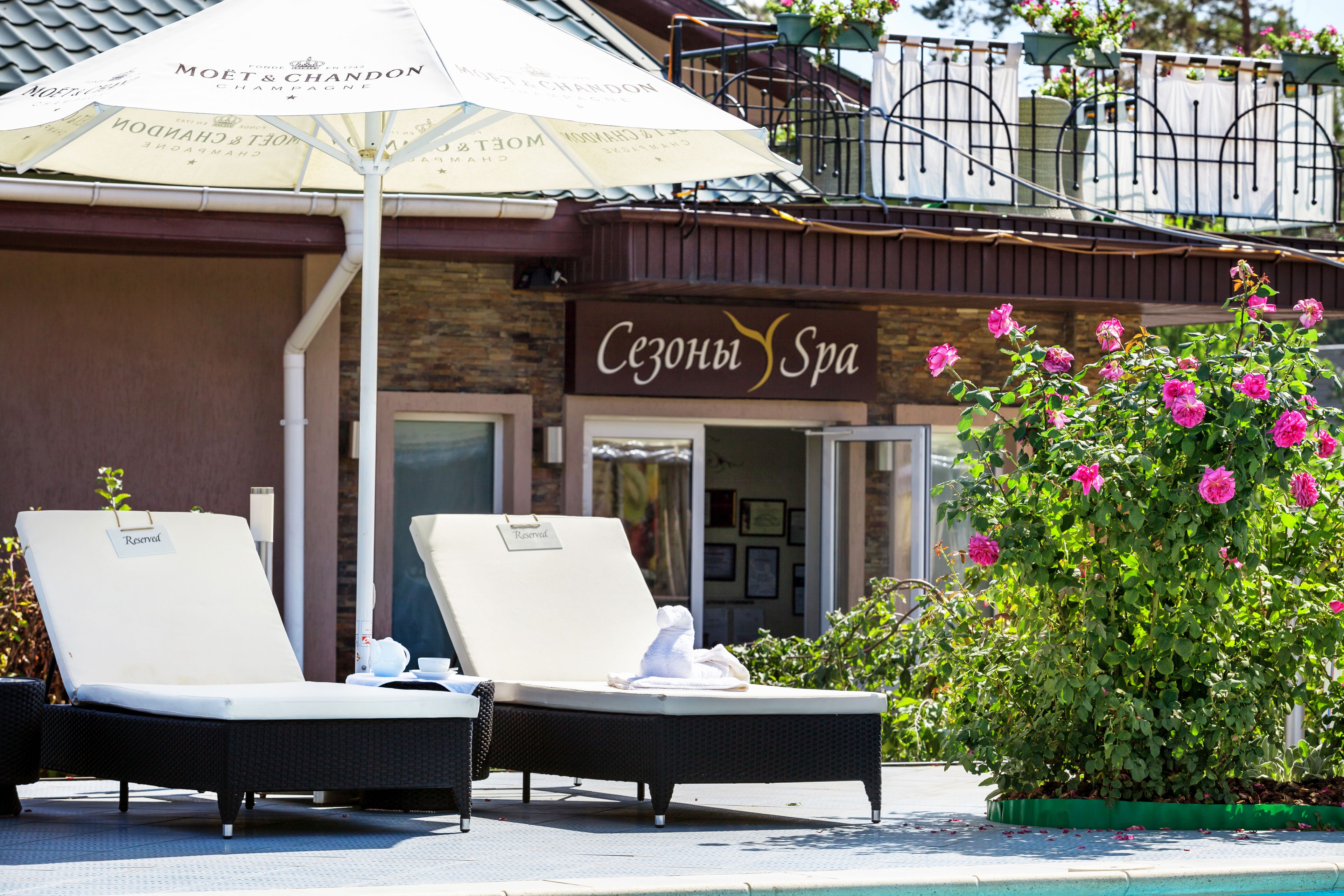 A spa with a sign reading "Сезонный Spa" and two lounge chairs with a Moët & Chandon umbrella.