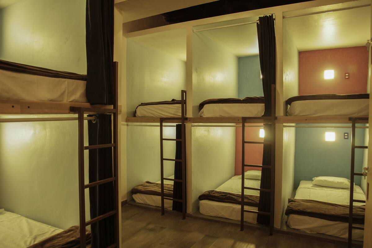 Une chambre de type dortoir, équipée de lits superposés, chacun ayant une échelle.