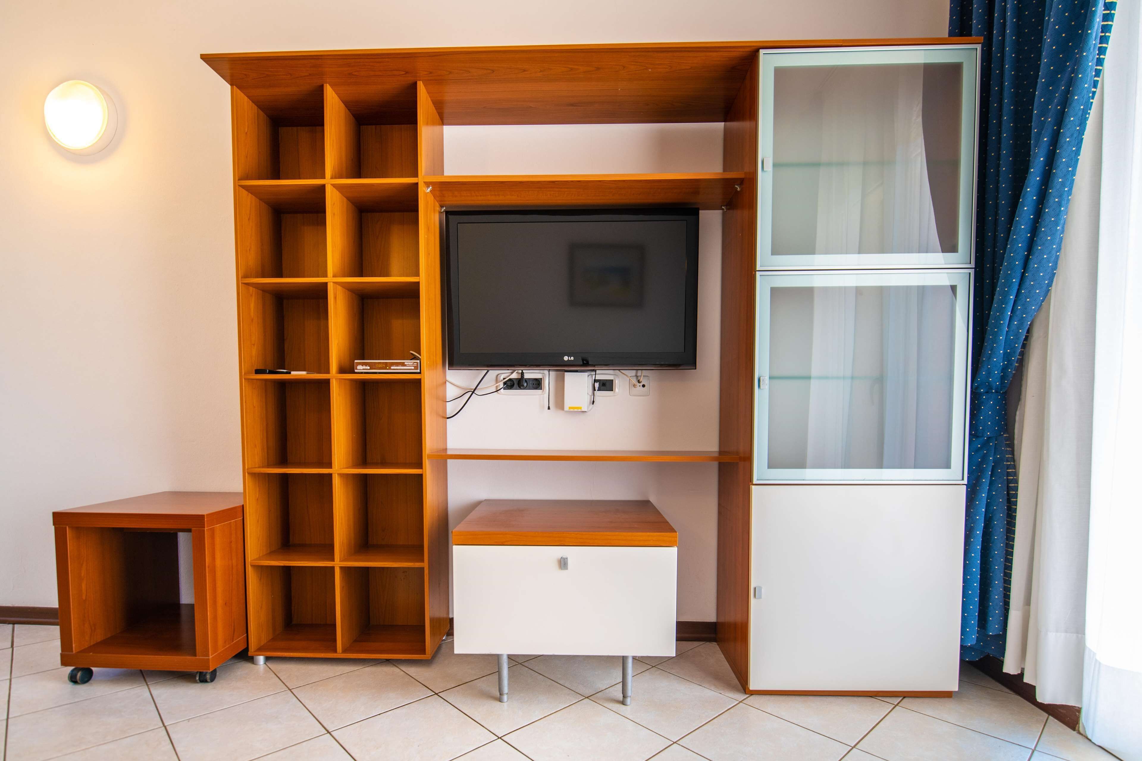 A compact entertainment unit with a TV, shelves, and a small cabinet.