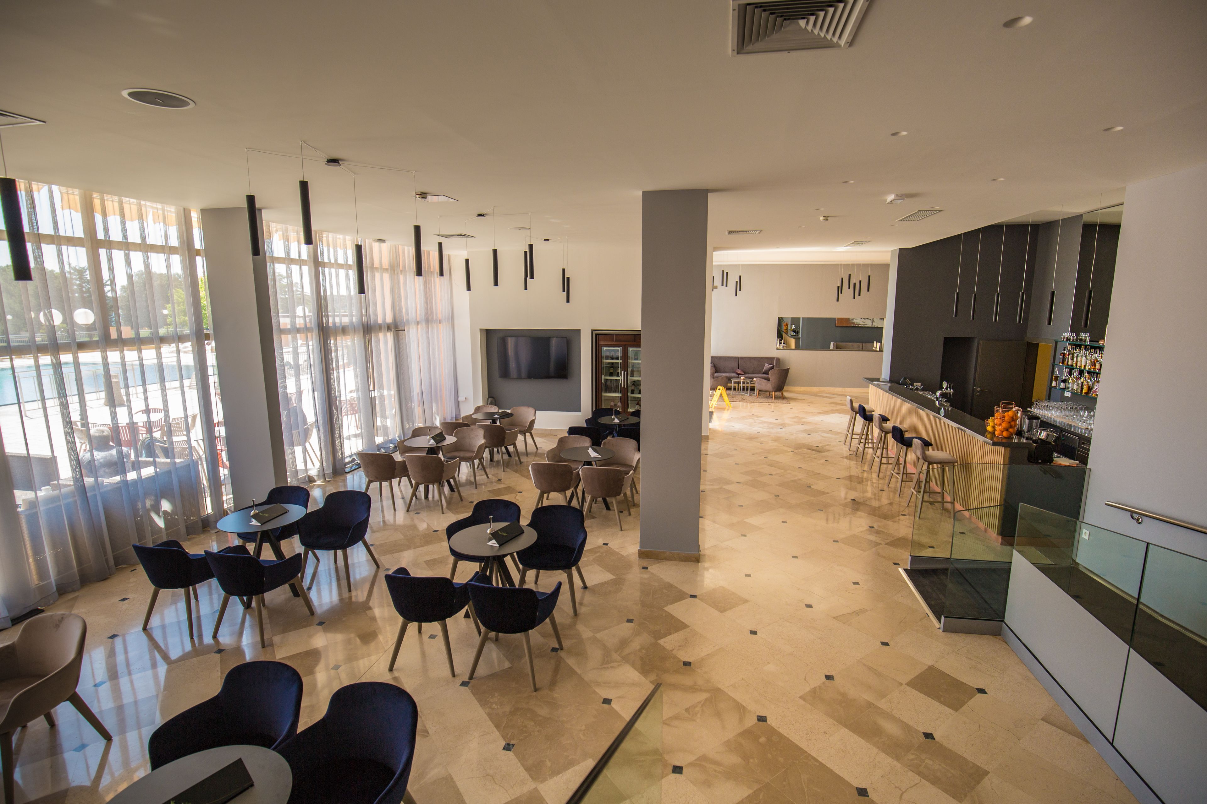 A spacious, modern lounge area with multiple seating options, a bar, and a kitchen area.