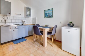 A compact kitchen with a dining area, a coffee machine, and a refrigerator.