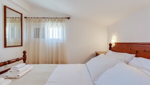 A neatly made bed with white linens, a wooden headboard, and a bedside table with a lamp. - Baresic Apartmani (Zadar)