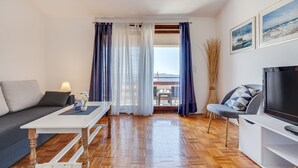 A modern living room with a sofa, a TV, and a dining table. - Baresic Apartmani (Zadar)