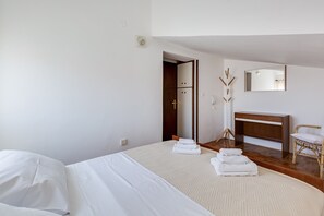A hotel room with a bed, a wooden dresser, a chair, and a mirror.