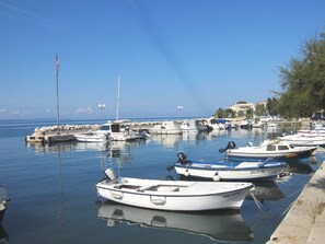 A marina with several boats docked, calm water, and a clear sky.
