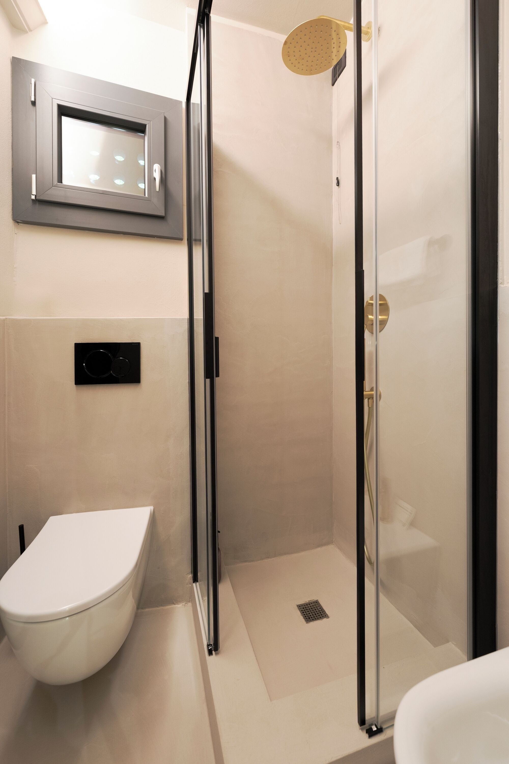A modern bathroom with a glass-enclosed shower, a toilet, and a sink.
