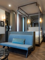 Una habitación de hotel moderna con una cama grande, un sofá, una mesita y un espejo.
