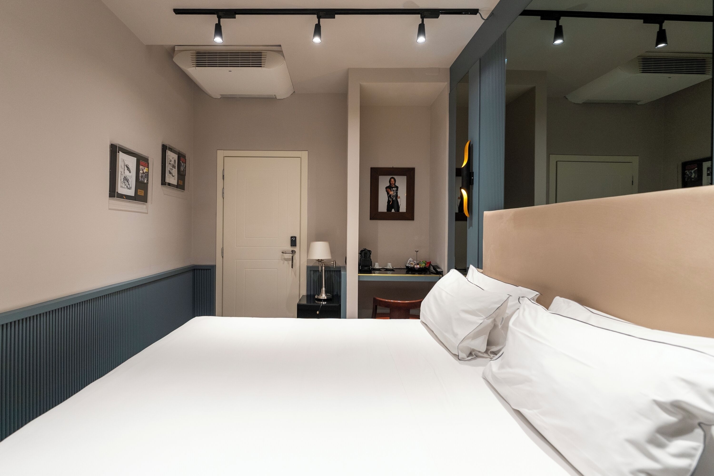 A neatly arranged hotel room with a large bed, a desk, a chair, and a mirror.