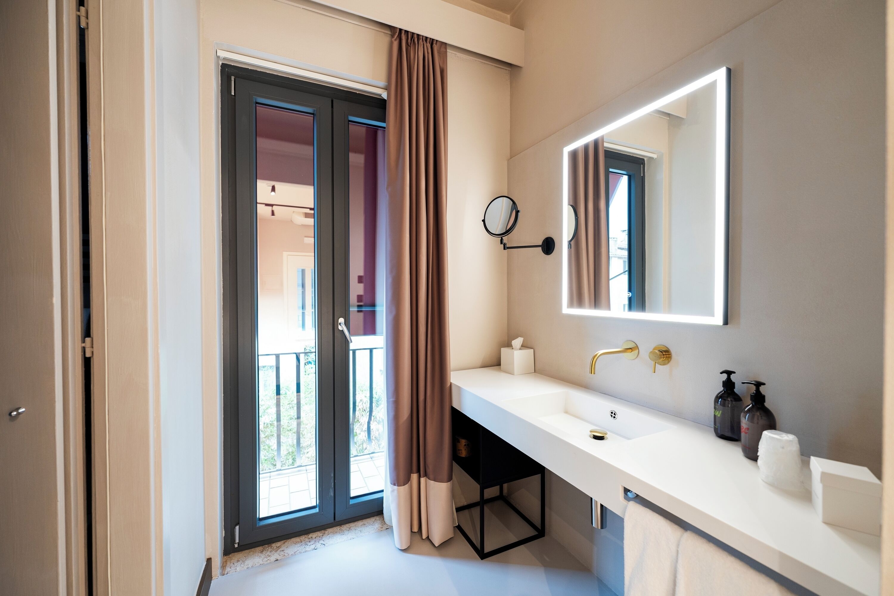 A modern bathroom with a large mirror, a white sink, and a black cabinet.