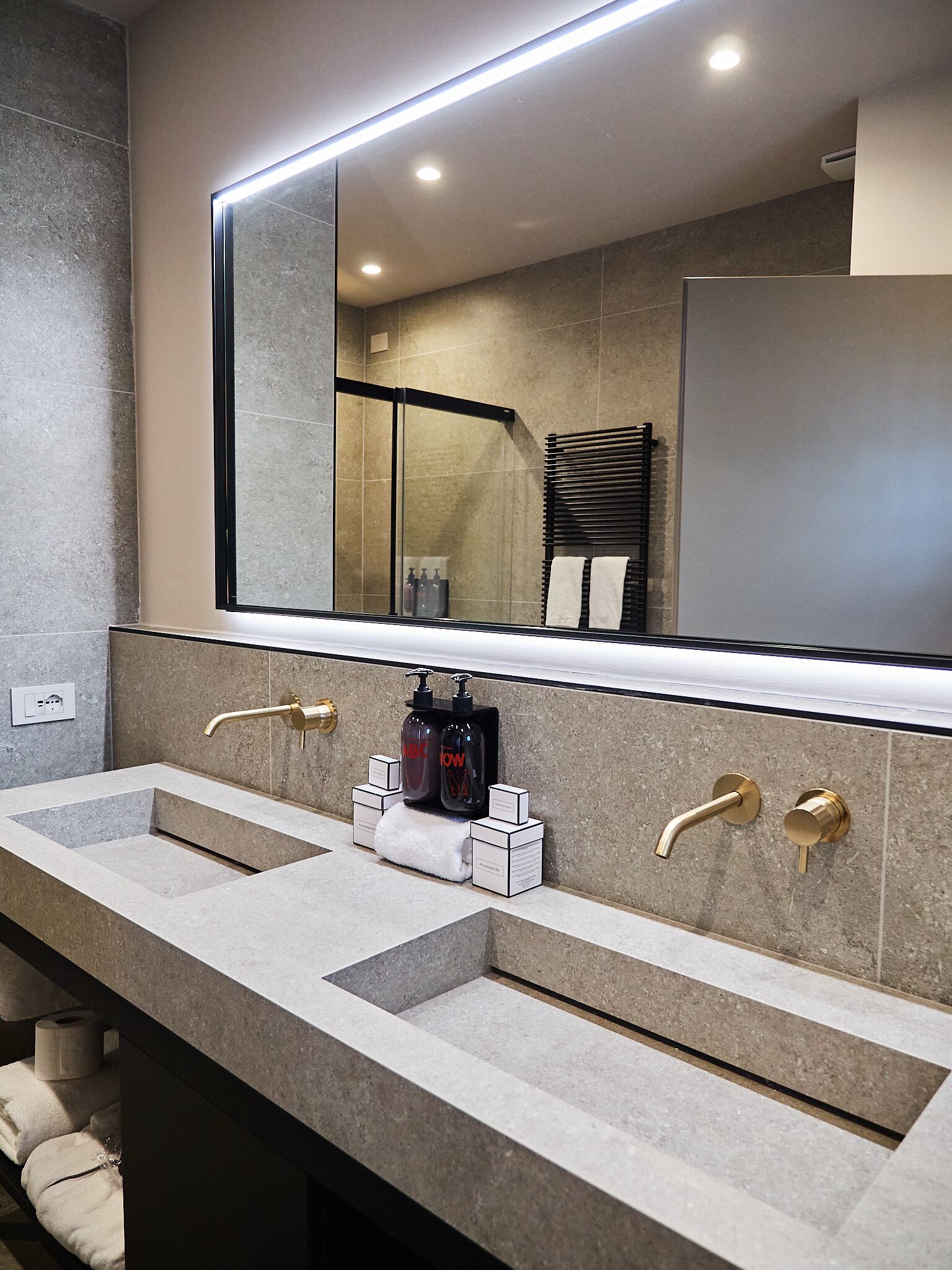 A modern bathroom with two sinks, a large mirror, and a towel rack.