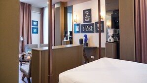 Een hotelkamer met een bed, een bureau, een stoel, een spiegel en ingekaderde foto's aan de muur.