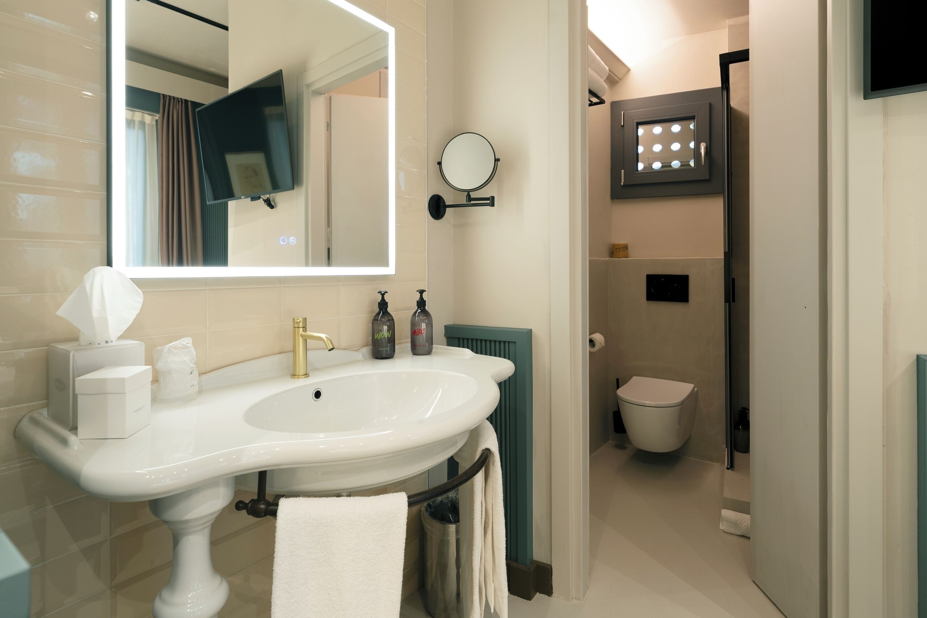 A bathroom with a white sink, a mirror, a towel rack, a toilet, and a shower area.