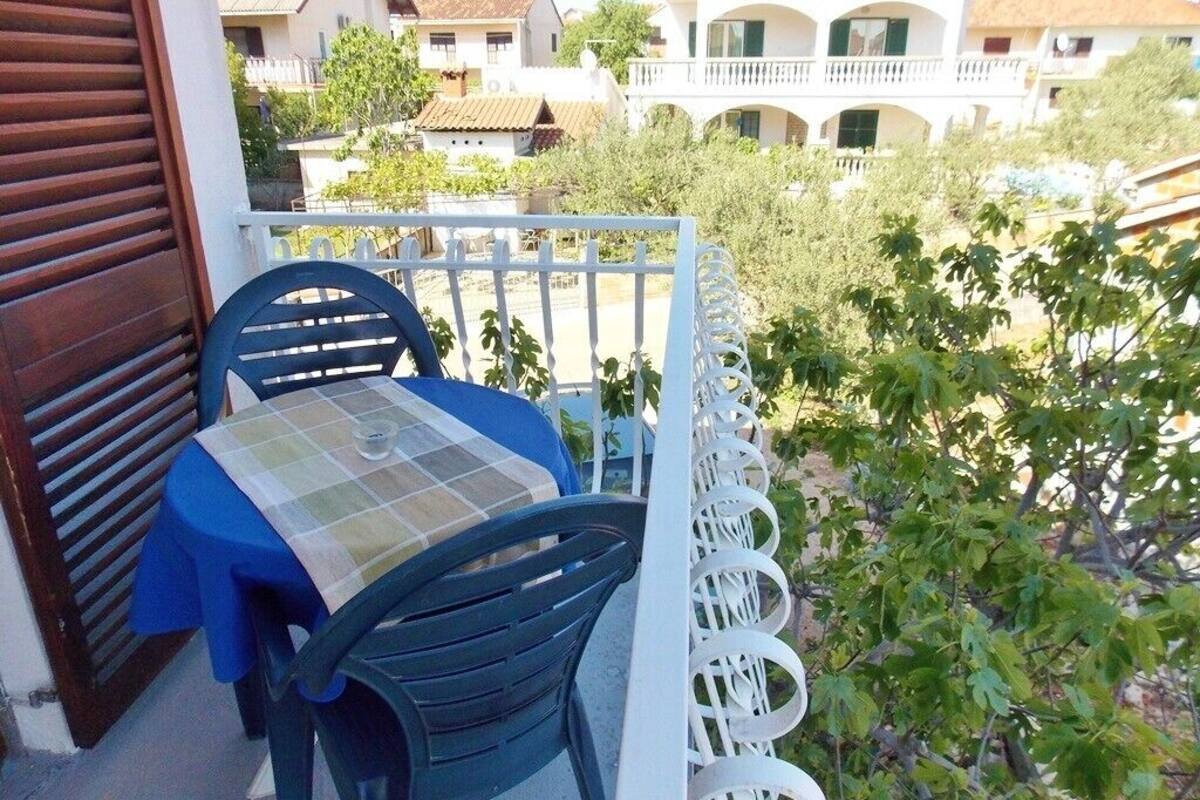 Un balcón con mesa y sillas, con vistas a una zona residencial con casas y vegetación.