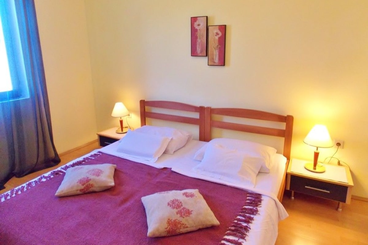 A neatly made bed with two pillows and two bedside lamps.