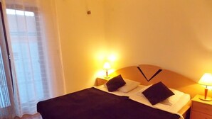A hotel room with a bed, two bedside lamps, a wooden headboard, and a window with sheer curtains. - Bakmaz Apartment (Vodice)
