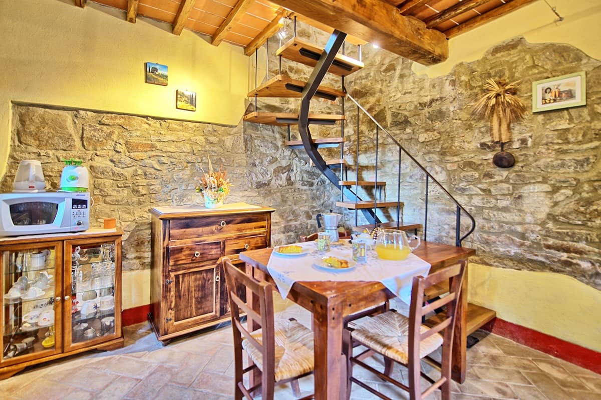 Ein rustikaler Essbereich mit Steinwand, einer Holztreppe und einem Tisch für zwei Personen.