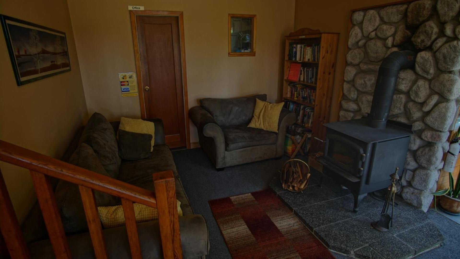 A cozy living room with a fireplace, a bookshelf, and a door labeled "Office".