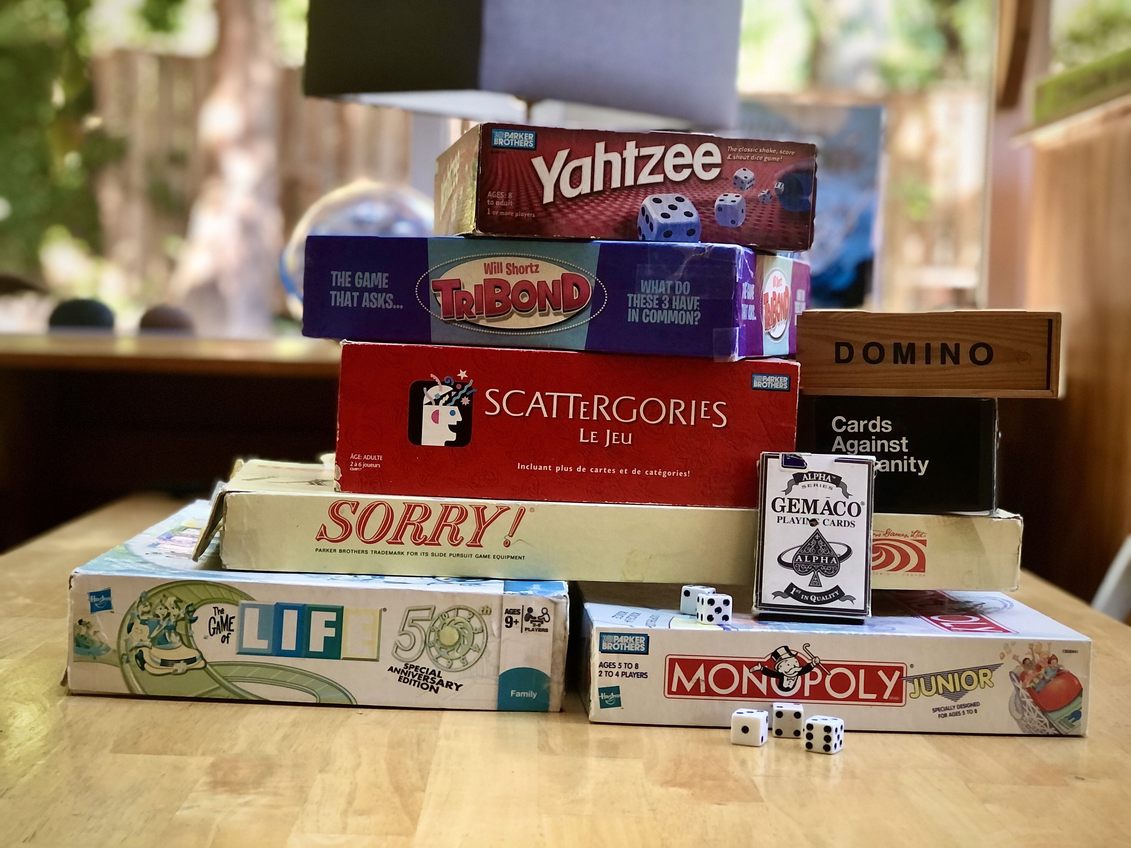 A variety of board games stacked on a table.