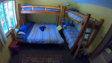 A bunk bed room with a window, a desk, and a patterned rug.