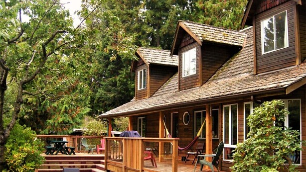 Une cabane en bois avec un porche, un espace salon extérieur et une petite terrasse.