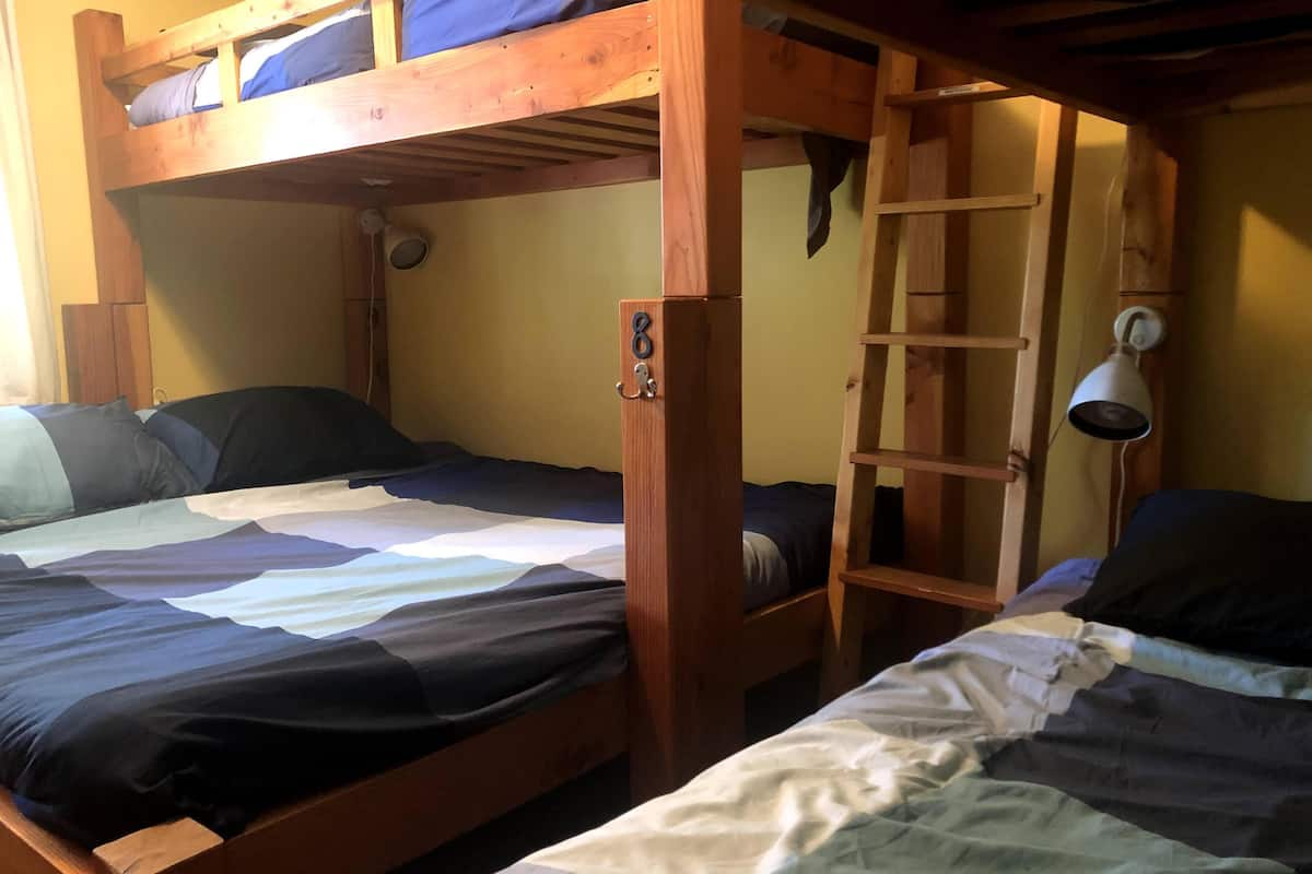 Een slaapkamer met een stapelbed, een bureau en een lamp.